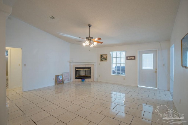 unfurnished living room featuring vaulted ceiling, light tile patterned floors, a tile fireplace, and ceiling fan