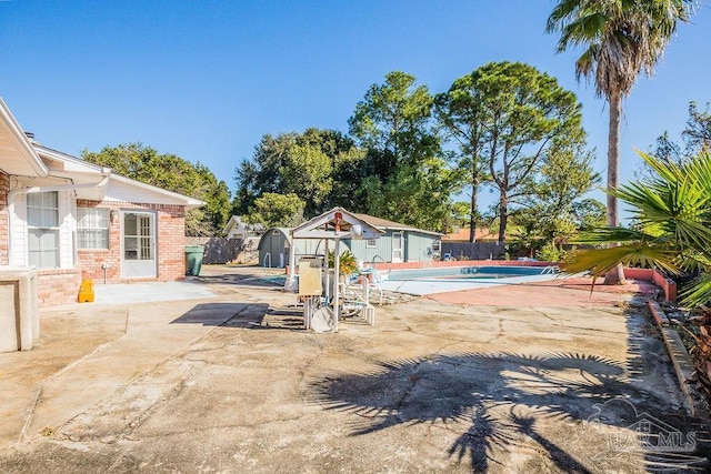 view of pool with a shed and a patio