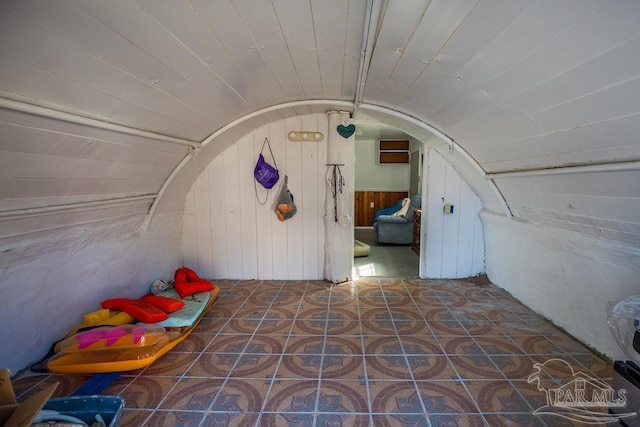 additional living space with wooden walls, vaulted ceiling, and tile patterned flooring