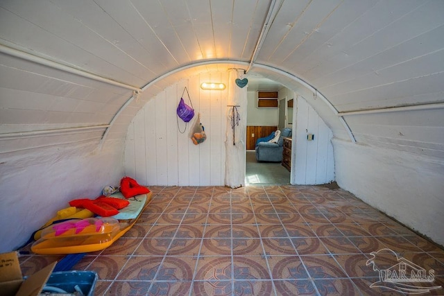 bonus room with lofted ceiling, wood walls, and tile patterned floors