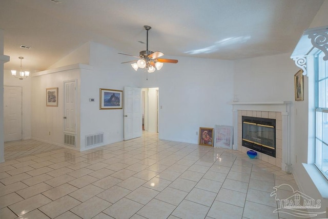 unfurnished living room with vaulted ceiling, a fireplace, ceiling fan with notable chandelier, and light tile patterned floors