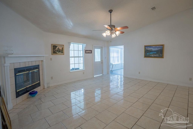 unfurnished living room featuring ceiling fan, light tile patterned flooring, a tile fireplace, and vaulted ceiling