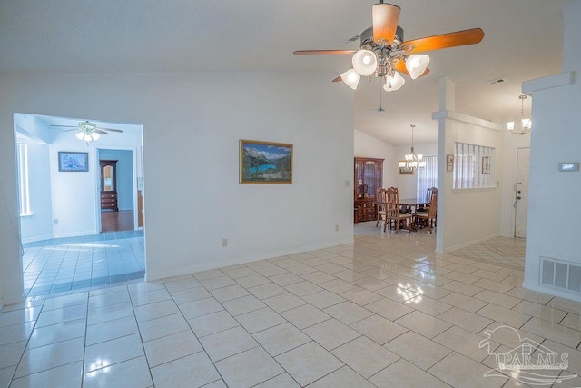 spare room with lofted ceiling, ceiling fan with notable chandelier, and light tile patterned floors