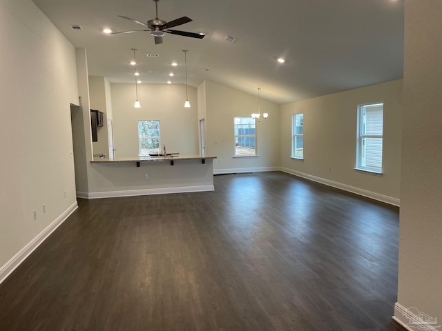 unfurnished living room featuring dark wood-type flooring, visible vents, baseboards, and ceiling fan with notable chandelier