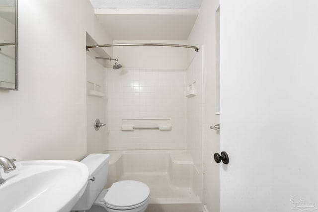 bathroom featuring sink, a tile shower, and toilet