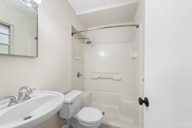 bathroom with a tile shower, sink, and toilet