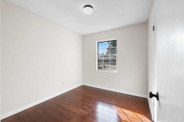 empty room featuring dark hardwood / wood-style flooring and a textured ceiling