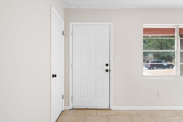 doorway to outside with light tile patterned floors and a textured ceiling