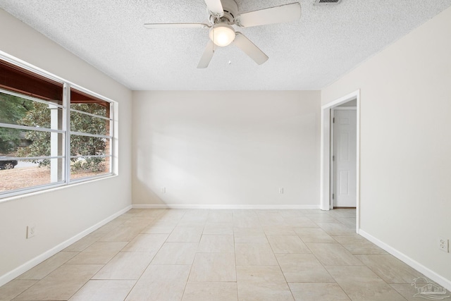 empty room featuring light tile patterned flooring, ceiling fan, and a textured ceiling