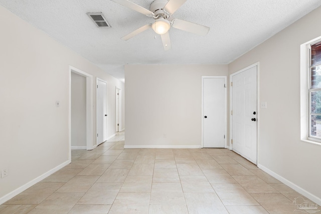 empty room with light tile patterned floors, a textured ceiling, and ceiling fan