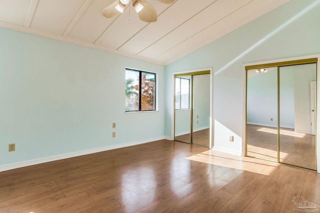 unfurnished bedroom featuring two closets, ceiling fan, lofted ceiling, and hardwood / wood-style flooring