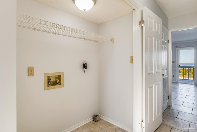 clothes washing area with washer hookup, light tile patterned floors, and a textured ceiling