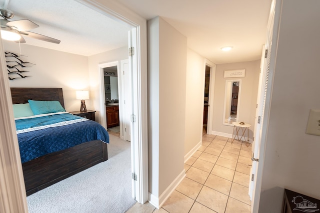 bedroom featuring ceiling fan, ensuite bath, baseboards, and light tile patterned floors
