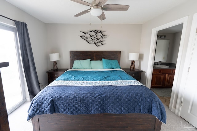 bedroom with multiple windows, light carpet, a ceiling fan, and a sink