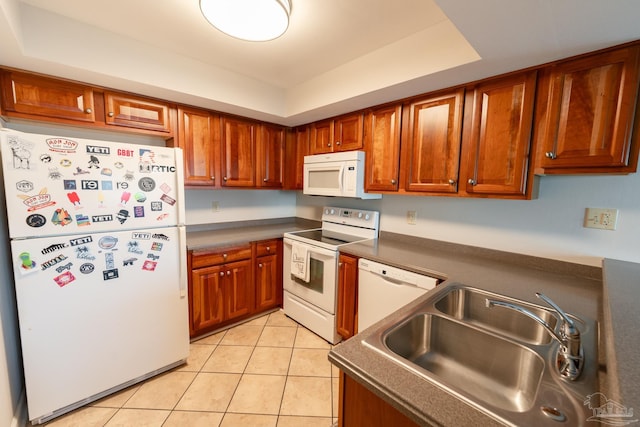 kitchen featuring light tile patterned floors, white appliances, a sink, brown cabinets, and dark countertops