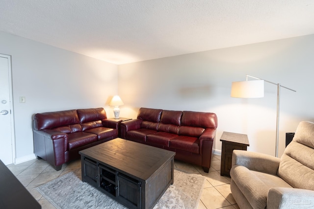 living area featuring light tile patterned floors, baseboards, and a textured ceiling