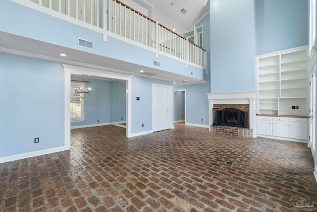 unfurnished living room with a towering ceiling, visible vents, a chandelier, and baseboards