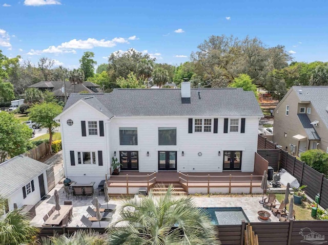 rear view of property featuring a deck, a fenced backyard, french doors, and a chimney