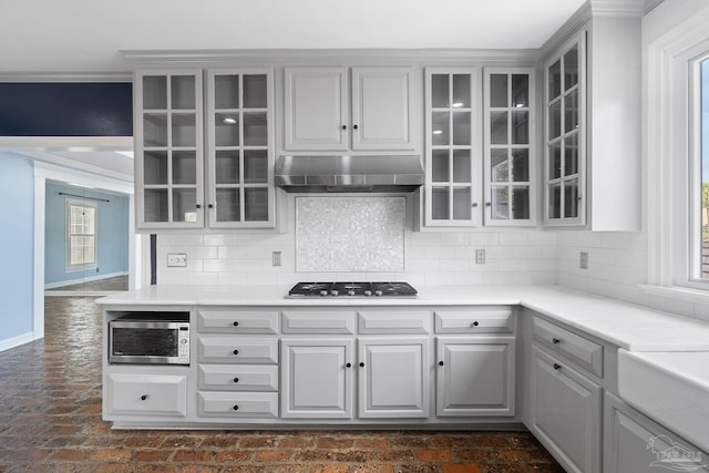 kitchen with ventilation hood, backsplash, gas cooktop, and stainless steel microwave