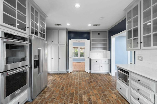 kitchen with appliances with stainless steel finishes, visible vents, light countertops, and backsplash