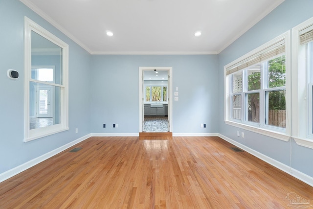 unfurnished room featuring baseboards, visible vents, ornamental molding, and light wood finished floors