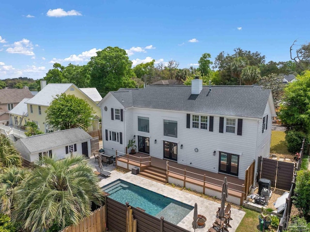 back of property featuring a chimney, a fenced backyard, a fenced in pool, a wooden deck, and french doors
