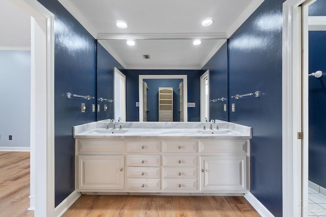 bathroom featuring wood finished floors, crown molding, and a sink