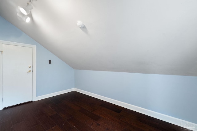 bonus room featuring baseboards, dark wood-style floors, and vaulted ceiling