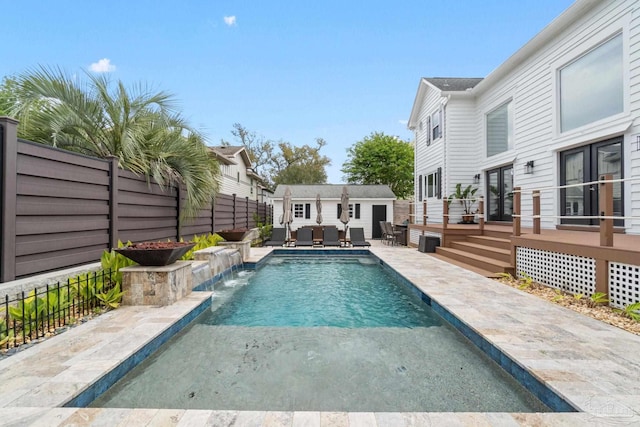 view of pool featuring a deck, a fenced backyard, an outdoor structure, a fenced in pool, and outdoor lounge area
