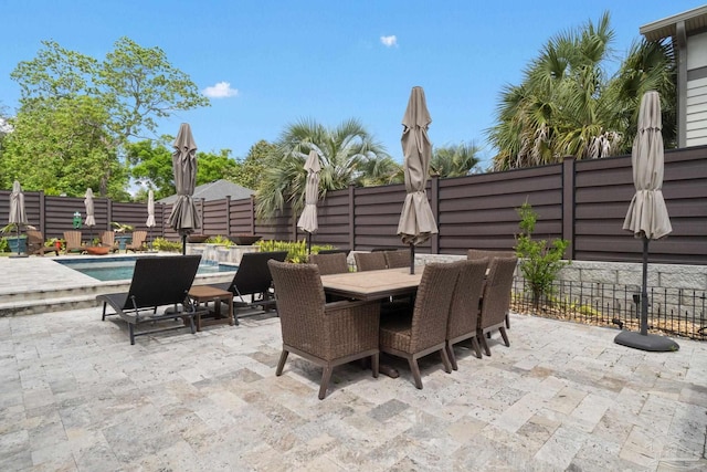 view of patio with outdoor dining space, a fenced backyard, and a fenced in pool
