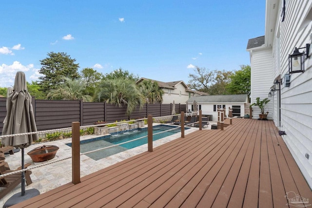 wooden deck with a fenced in pool, an outdoor fire pit, and a fenced backyard