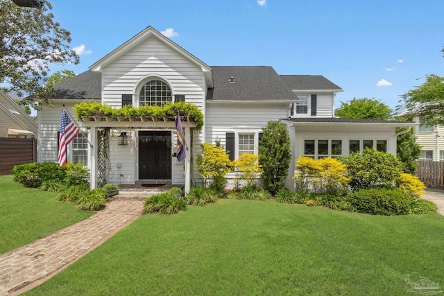 view of front of home with a front lawn, roof with shingles, and fence