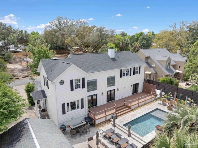 rear view of house featuring a deck, a chimney, a fenced backyard, a fenced in pool, and outdoor dining area