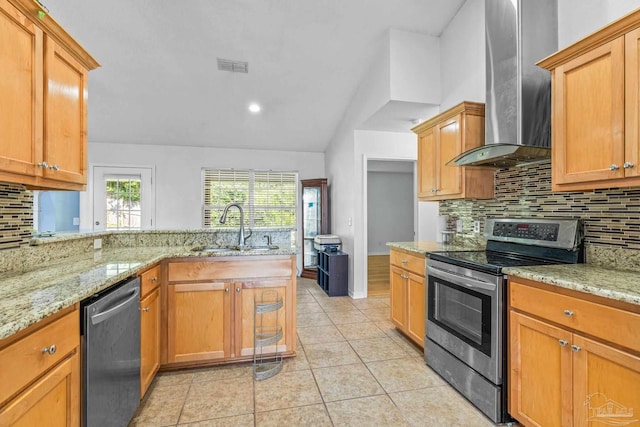 kitchen featuring stainless steel appliances, wall chimney range hood, light tile patterned floors, decorative backsplash, and light stone countertops