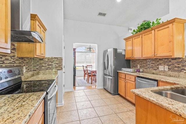 kitchen featuring wall chimney range hood, appliances with stainless steel finishes, light stone countertops, and tasteful backsplash