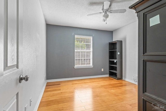 living room with a textured ceiling, light wood-type flooring, and ceiling fan