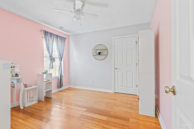 bedroom with light hardwood / wood-style floors, a textured ceiling, and ceiling fan