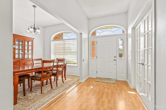 foyer entrance with a chandelier, light wood-type flooring, and a textured ceiling