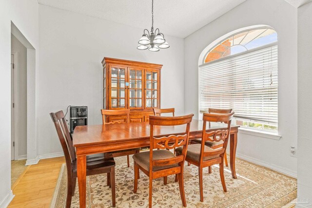 dining space featuring an inviting chandelier, a textured ceiling, and light hardwood / wood-style flooring