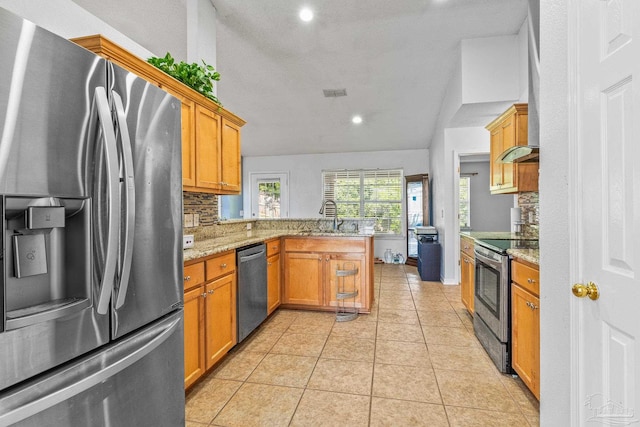 kitchen featuring appliances with stainless steel finishes, sink, kitchen peninsula, backsplash, and light tile patterned flooring