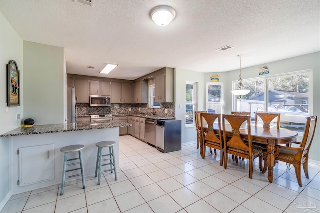 kitchen featuring kitchen peninsula, appliances with stainless steel finishes, sink, light tile patterned flooring, and decorative backsplash