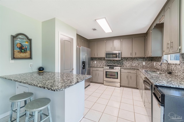 kitchen featuring sink, kitchen peninsula, stone counters, and stainless steel appliances