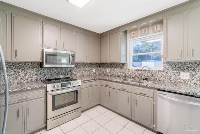 kitchen featuring stainless steel appliances, sink, backsplash, light tile patterned floors, and gray cabinetry