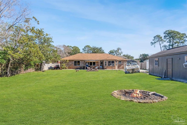 rear view of property featuring a fire pit and a lawn