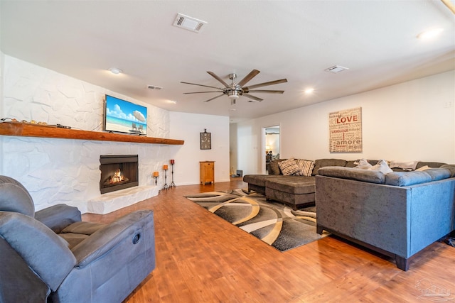 living room featuring ceiling fan, hardwood / wood-style floors, and a fireplace