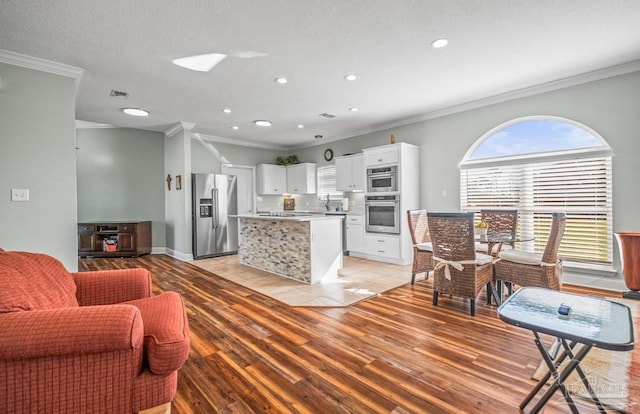 living room with ornamental molding, sink, light hardwood / wood-style flooring, and a textured ceiling