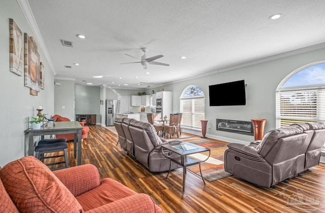 living room featuring ornamental molding, dark wood-type flooring, plenty of natural light, and ceiling fan