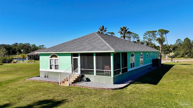 rear view of house featuring a lawn and a sunroom