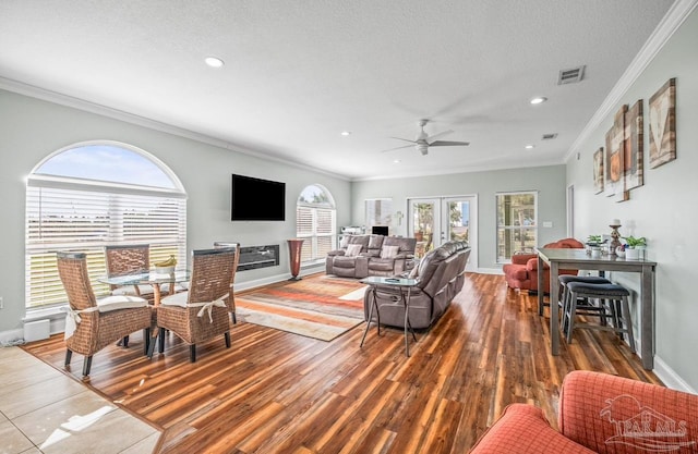 living room featuring hardwood / wood-style floors, ceiling fan, a textured ceiling, ornamental molding, and french doors