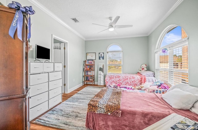 bedroom with a textured ceiling, multiple windows, light wood-type flooring, and ceiling fan